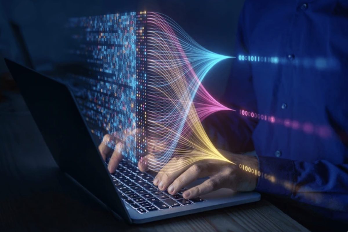 Manos escribiendo en una laptop con flujos de datos de colores emanando de la pantalla — laboratorio de comercio con inteligencia artificial